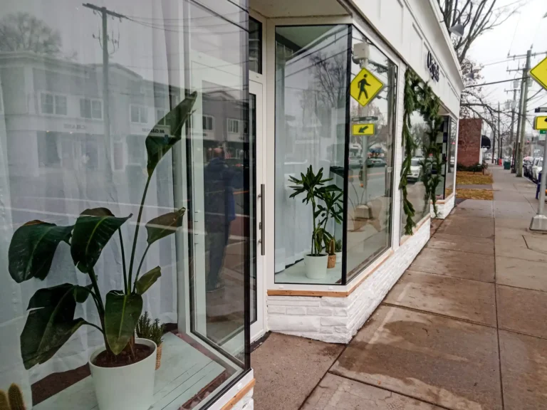 Storefront seen from the pathway, with reflections of the street in the glass window.